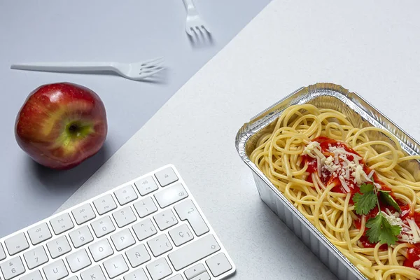 職場での昼食は自家製で健康的なスパゲティトマトとチーズをコンピュータキーボードで作業台で オフィスのコンセプトのためのホームフード 食べ物を奪う — ストック写真