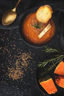 Ev yapımı ve sağlıklı balkabağı kreması ve koyu arkaplanda yukarıdan gelen ekmek. Düz yatıyordu