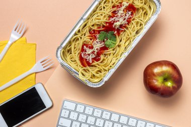 İş yerinde öğle yemeği ve bilgisayar klavyeli domates ve peynirli sağlıklı spagetti. Ofis konsepti için ev yemeği. Yemeği götür.