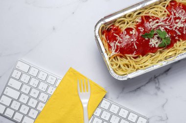 İş yerinde öğle yemeği ve bilgisayar klavyeli domates ve peynirli sağlıklı spagetti. Ofis konsepti için ev yemeği. Yemeği götür.