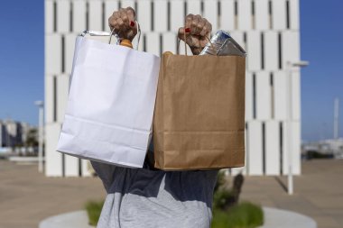 Geri dönüşümlü kağıt taşıyan tanınmayan bir kadın yiyecek poşetini alıp götürdü.