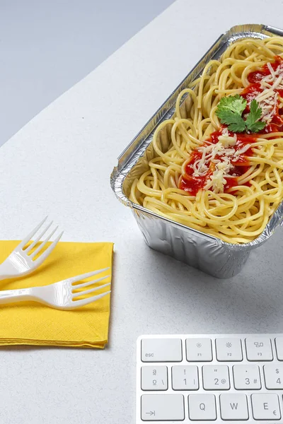 職場での昼食は自家製で健康的なスパゲティトマトとチーズをコンピュータキーボードで作業台で オフィスのコンセプトのためのホームフード 食べ物を奪う — ストック写真