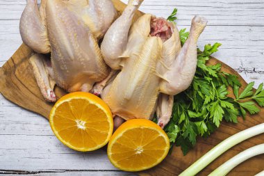 Pişirmeye hazır çiğ sebzeli koka tavukları. Havuç, pırasa; tatlı patates; yukarıdan maydanoz. Düz yatıyordu