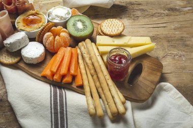 Sağlıklı Brunch masası jambon, çilek, kivi; ekmek; kurabiye; peynir, havuç, mandalina, humus; teslimat konsepti