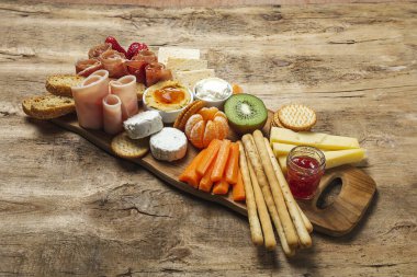 Sağlıklı Brunch masası jambon, çilek, kivi; ekmek; kurabiye; peynir, havuç, mandalina, humus; teslimat konsepti