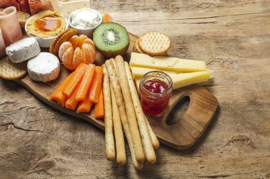 Sağlıklı Brunch masası jambon, çilek, kivi; ekmek; kurabiye; peynir, havuç, mandalina, humus; teslimat konsepti