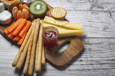 Sağlıklı Brunch masası jambon, çilek, kivi; ekmek; kurabiye; peynir, havuç, mandalina, humus; teslimat konsepti