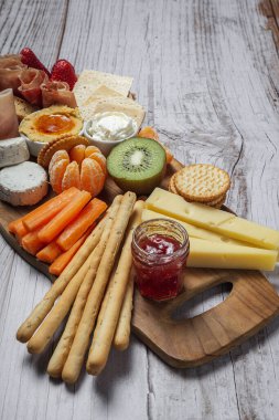 Sağlıklı Brunch masası jambon, çilek, kivi; ekmek; kurabiye; peynir, havuç, mandalina, humus; teslimat konsepti