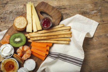 Sağlıklı Brunch masası jambon, çilek, kivi; ekmek; kurabiye; peynir, havuç, mandalina, humus; teslimat konsepti