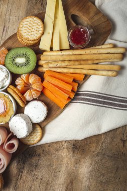 Sağlıklı Brunch masası jambon, çilek, kivi; ekmek; kurabiye; peynir, havuç, mandalina, humus; teslimat konsepti