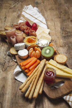 Sağlıklı Brunch masası jambon, çilek, kivi; ekmek; kurabiye; peynir, havuç, mandalina, humus; teslimat konsepti