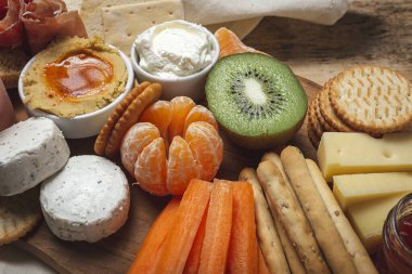 Sağlıklı Brunch masası jambon, çilek, kivi; ekmek; kurabiye; peynir, havuç, mandalina, humus; teslimat konsepti