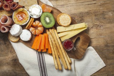 Sağlıklı Brunch masası jambon, çilek, kivi; ekmek; kurabiye; peynir, havuç, mandalina, humus; teslimat konsepti