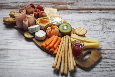 Sağlıklı Brunch masası jambon, çilek, kivi; ekmek; kurabiye; peynir, havuç, mandalina, humus; teslimat konsepti