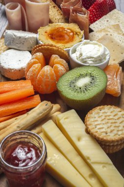 Sağlıklı Brunch masası jambon, çilek, kivi; ekmek; kurabiye; peynir, havuç, mandalina, humus; teslimat konsepti