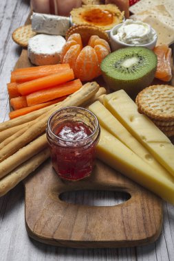 Sağlıklı Brunch masası jambon, çilek, kivi; ekmek; kurabiye; peynir, havuç, mandalina, humus; teslimat konsepti