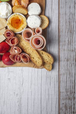 Sağlıklı Brunch masası jambon, çilek, kivi; ekmek; kurabiye; peynir, havuç, mandalina, humus; teslimat konsepti