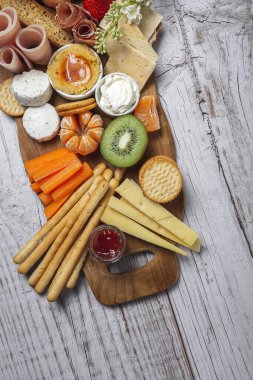 Sağlıklı Brunch masası jambon, çilek, kivi; ekmek; kurabiye; peynir, havuç, mandalina, humus; teslimat konsepti