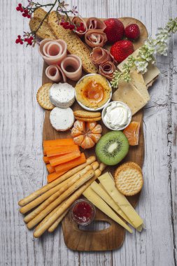 Sağlıklı Brunch masası jambon, çilek, kivi; ekmek; kurabiye; peynir, havuç, mandalina, humus; teslimat konsepti