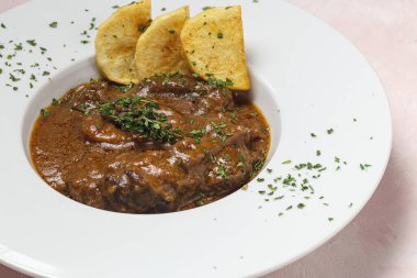 Ev yapımı Osso Buco eti aromatik bitki sosu, kırmızı şarap ve patates kızartması.