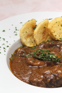 Ev yapımı Osso Buco eti aromatik bitki sosu, kırmızı şarap ve patates kızartması.