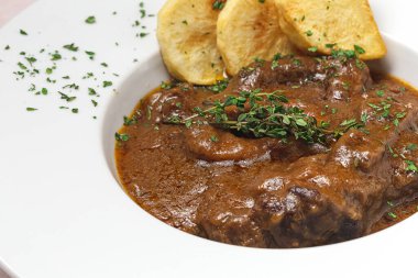 Ev yapımı Osso Buco eti aromatik bitki sosu, kırmızı şarap ve patates kızartması.