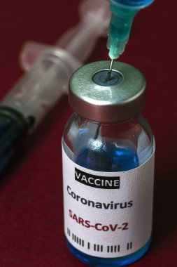 COVID-19 aşısı olan şeffaf cam şişeler, renkli arka planda şırıngalar. Seçili odak.
