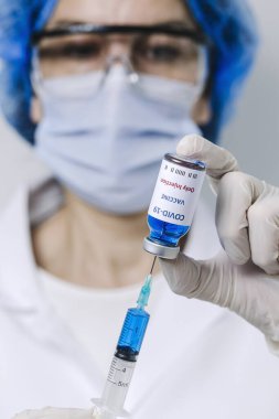COVID-19 aşısı araştırmacıların elinde tanınmayan kadın doktor Coronavirus aşısı için şırınga ve şişe tutuyor. Corona virüsü tedavisi kavramı