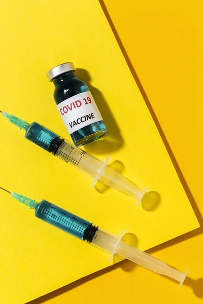 透明玻璃瓶 装有Covid 19疫苗 上面有彩色背景的注射器 — 图库照片