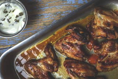 Ahşap masada pişirme tepsisinde ev yapımı kızarmış tavuk kanadı.