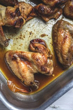 Ahşap masada pişirme tepsisinde ev yapımı kızarmış tavuk kanadı.