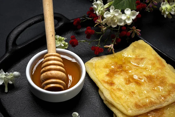 Ev yapımı ve geleneksel Arap rghaif ya da koyu arkaplanda bal ve krem peynirli msemen. Fas Yemekleri