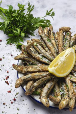 Beyaz arka planda limonlu ve maydanozlu geleneksel kızarmış ançüez. Deniz ürünleri konsepti