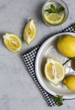 Gri arka planda yeşil nane yapraklı taze limonlar. Düz yatıyordu