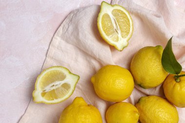 Yukarıdan pembe arka planda yeşil nane yapraklı taze limonlar. Düz yatıyordu