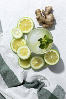 Buzlu ev yapımı cam limonata ve beyaz arka planda gün ışığında nane şekeri.