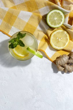 Buzlu ev yapımı cam limonata ve beyaz arka planda gün ışığında nane şekeri.