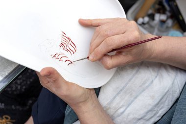 Tanımlanamayan kadın elleriyle seramik tabakları boyuyor. Sanatçılık konsepti