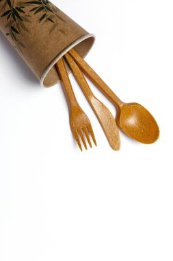 Plastik tek kullanımlık sofra takımı, çatallar, kaşıklar, beyaz arka planda bardaklar. Çevreye önem vermek. Sorun geri dönüşüm. Tekrar kullan. Metin için yer.