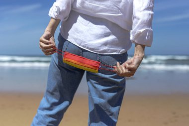 Plajda yüzü LGBT renginde bir maske takan orta yaşlı lezbiyen kadın..