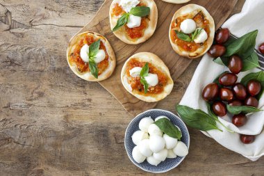 Domates, mozzarella ve fesleğenli ev yapımı mini pizza. Geleneksel İtalyan yemeği.