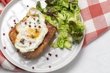 Yukardan beyaz arka planda brioche ve marul salatası ile ev yapımı sahanda yumurta.