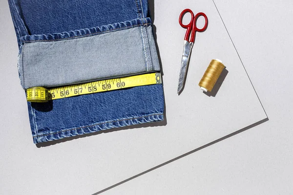 Handicraft, clothing repair. Ripped blue jeans sewing accessories with colorful background from above. Flat lay