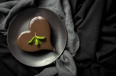 Siyah arka planda ev yapımı kalp şeklinde çikolatalı pasta.