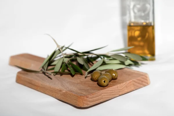 Оливковое масло с оливками на белом фоне — стоковое фото