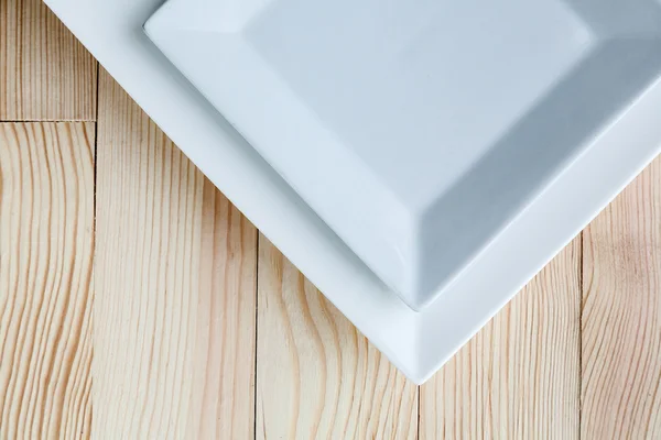 Square white plates over wooden table — Stock Photo, Image