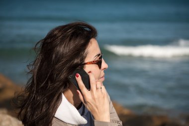 Genç, güzel, gülümseyen kadın cep telefonuyla konuşuyor. 