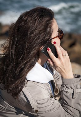 Genç, güzel, gülümseyen kadın cep telefonuyla konuşuyor. 