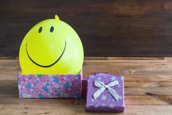 Ballon jaune avec sourire et boîte cadeau — Photo