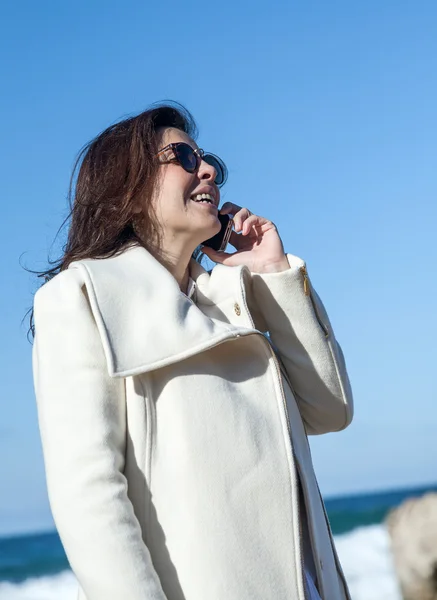 Aantrekkelijke vrouw praten via de telefoon naar de zee — Stockfoto